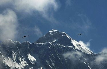 FILE – In this May 27, 2019, file photo, birds fly as Mount Everest is seen from Namche Bajar, Solukhumbu district, Nepal. Nepal is expecting hundreds of foreigners to attempt to scale the highest Himalayan peaks despite the pandemic, an official said Wednesday.  (AP Photo/Niranjan Shrestha, File) NME101 NME101