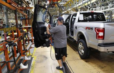 FILE- In this Sept. 27, 2018, file photo a United Auto Workers assemblyman installs the front doors on a 2018 Ford F-150 truck being assembled at the Ford Rouge assembly plant in Dearborn, Mich. Ford Motor Co. said Tuesday, Dec. 17, 2019, that it is adding 3,000 jobs at two factories in the Detroit area and investing $1.45 billion to build new pickup trucks, SUVs, and electric and autonomous vehicles. At the Dearborn truck plant $700 million will be invested. (AP Photo/Carlos Osorio, File)