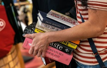 FILE — A customer carries books through the Strand bookstore in New York, Oct. 25, 2020. The pandemic altered how readers discover and buy books, and drove sales for celebrities and best-selling authors while new and lesser known writers struggled. (Jeenah Moon/The New York Times)