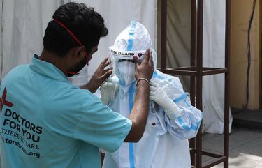 FILE- In this April 19, 2021, file photo, a health worker adjusts the face shield of another as she prepares to go inside a quarantine center for COVID-19 patients in New Delhi, India. As India suffers a bigger, more infectious second wave with a caseload of more than 300,000 new cases a day, the countryâ€™s healthcare workers are bearing the brunt of the disaster. (AP Photo/Manish Swarup, File) IHW103 IHW103