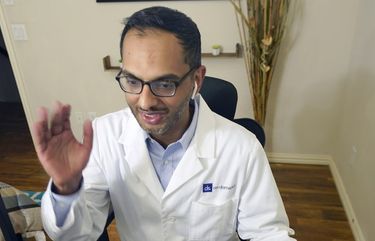 Medical director of Doctor on Demand Dr. Vibin Roy waves good-bye to a patient at the conclusion of an online primary care visit conducted from his home, Friday, April 23, 2021, in Keller, Texas.  Some U.S. employers and insurers want you to make telemedicine your first choice for most doctor visits. Retail giant Amazon and several insurers have started or expanded virtual-first care plans to get people thinking telemedicine routinely, even for annual checkups.  (AP Photo/LM Otero) TXMO106 TXMO106