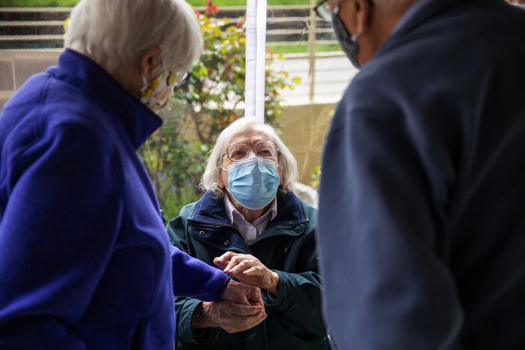Lorraine Molzahn greets Phyllis and Norman Swenson, who are also residents at The Hearthstone, during Lorraine’s 100th birthday party on Sunday, April 25, 2021. The Swensons used to bring Molzahn to church with them on Sundays. Molzahn was excited to see and welcome family and friends to her in-person birthday party, one of the first times she was able to be around a large group of people since the start of the pandemic. (Amanda Snyder / The Seattle Times)