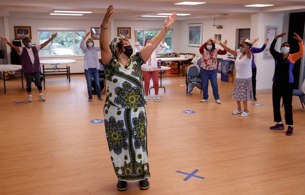 Afua Kouyate, executive director of the ADEFUA Cultural Education Workshop, leads a limited capacity, socially distanced West African dance class for fully vaccinated seniors at the Central Area Senior Center. “It’s an honor, a humbling experience to work with our elders in this cultural art experience of dance movement,” she says. “They are strong. They have a lot of energy. It’s a weekly social hub.” (Erika Schultz / The Seattle Times)