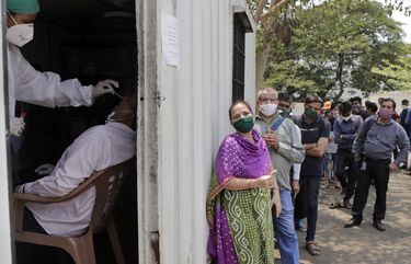A health worker takes a nasal swab sample of a person to test for COVID-19 as others wait for their turn outside a field hospital in Mumbai, India, Thursday, May 6, 2021. Infections in India hit another grim daily record on Thursday as demand for medical oxygen jumped seven-fold and the government denied reports that it was slow in distributing life-saving supplies from abroad. (AP Photo/Rajanish Kakade)