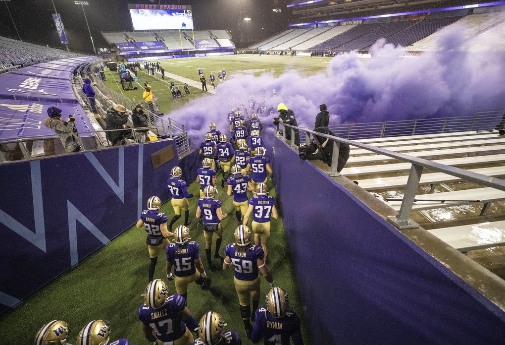 The University of Washington football team enters an empty Husky Stadium to start its 2020 season in November. The Pac-12 conference relied on an antigen test to screen players for coronavirus during the abbreviated season, but, behind the scenes, a debate raged over whether the tests could live up to their promise. (Dean Rutz / The Seattle Times)