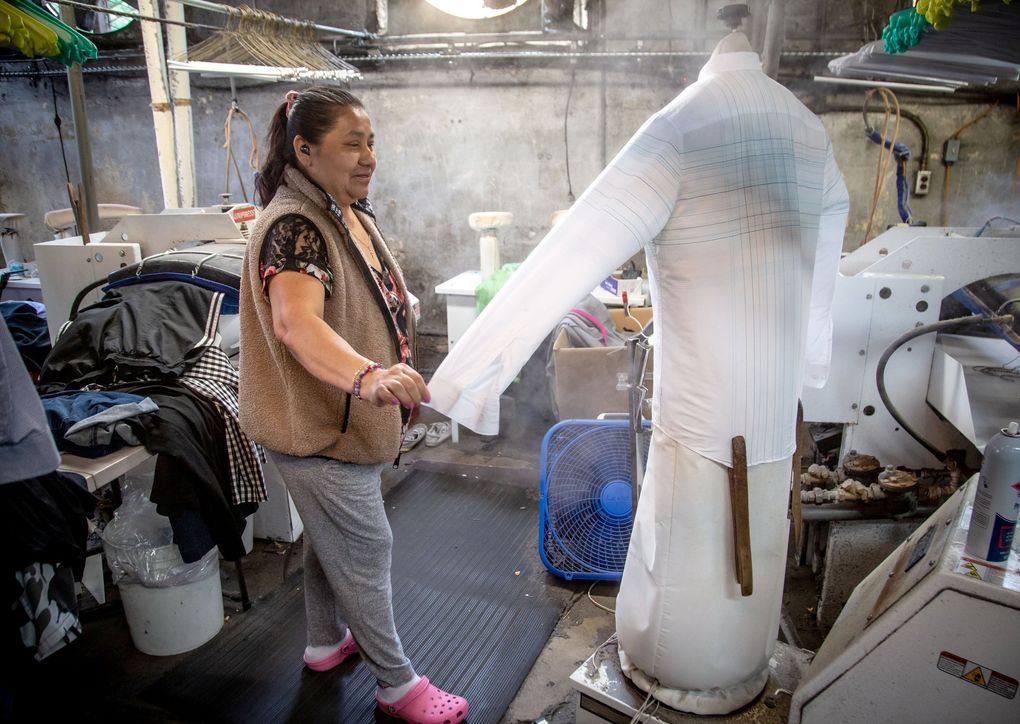 Rosa Hernandez dries a shirt at Sig Samuels Dry Cleaners in Atlanta in April. Co-owner Steve Collins says he cut his staff from a dozen to seven people who are coming in only three days a week. (Steve Schaefer for The Atlanta Journal-Constitution)
