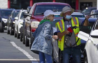 A customer helps pumping gas at Costco, as other wait in line, on Tuesday, May 11, 2021, in Charlotte, N.C. Colonial Pipeline, which delivers about 45% of the fuel consumed on the East Coast, halted operations last week after revealing a cyberattack that it said had affected some of its systems. (AP Photo/Chris Carlson) NCCC102 NCCC102