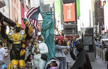Three visitors from Baltimore pose for photos with costumed performers in New York’s Times Square on May 1, 2021.  The number of tourists to New York City plunged to 22 million last year from 66 million in 2019. (Kirsten Luce/The New York Times) XNYT203 XNYT203