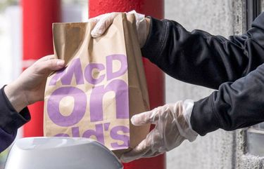 An employee hands an order to a customer at a McDonald’s drive-thru in Oakland, Calif. The company said it would raise starting wages at its company-owned outlets.