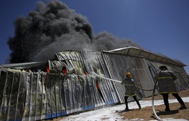 Palestinian firefighters work to extinguish a fire at a paint factory after it was hit by an Israeli airstrike, in Rafah, Gaza Strip, Tuesday, May 18, 2021. (AP Photo/Yousef Masoud) GAZ104 GAZ104