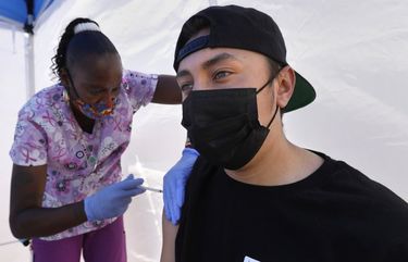 Los Angeles, California—May 12, 2021—At the East Los Angeles Civic Center, St. John’s Well Child & Family Center runs a vaccine clinic. Tanya Mitchell, a certified medical assistant, left, administers his a vaccinate to Richard Ayala, age 18, on California on May 12, 2021. (Carolyn Cole / Los Angeles Times)