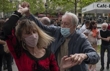 A couple with protective masks on dance at Republic square in Paris, Sunday, May 23, 2021. Cinemas, as cafe and restaurant terraces, museums, and theaters are reopening their doors after a shutdown of more than six months in the first stage of a government strategy to incrementally lift restrictions to stave off COVID-19, and give the French back some of their signature “joie de vivre.” (AP Photo/Rafael Yaghobzadeh) RAF103 RAF103