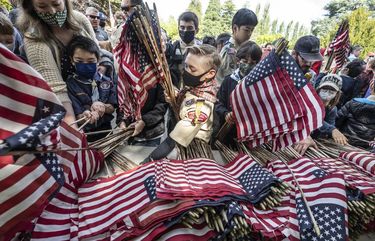 Monday, May 31, 2021. Lines Only. LO. Scouts rush the table to pick up ceremonial flags including Jared Petras, 10, at center, from Shorelines Pack 319 at the 95th Annual Memorial Day at Washelli Memorial Cemetery. Each of the 5,000 white upright marble markers received a flag placed by scouts, community members and veterans. 217282