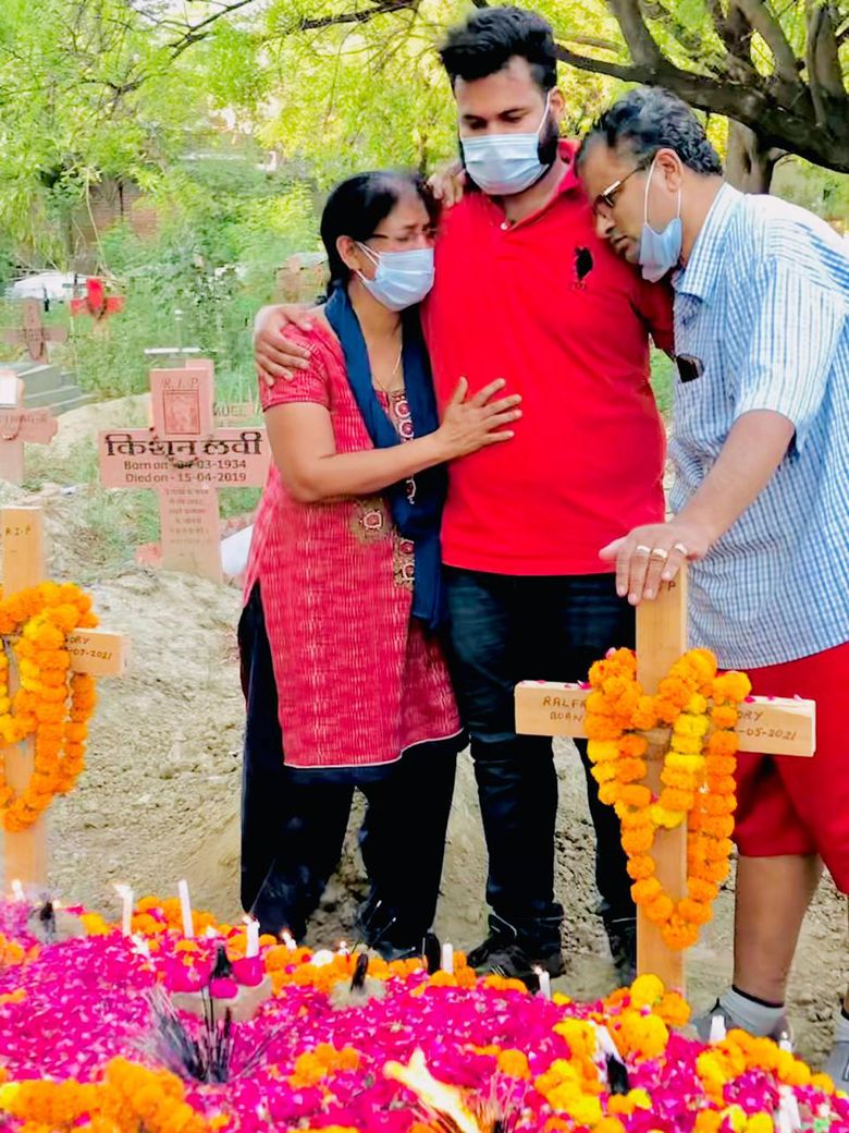 Soja Gregory, left, and Gregory Raymond Raphael, right, grieve with their eldest son, Nelfred Raphael Gregory, at St Luke’s cemetery after the burial of their twins Joefred and Ralfred in Meerut, near New Delhi, in May 2021. The story of the young computer engineers who lived and died together has spread fast and wide on Indian social media, puncturing this nation’s numbing pandemic statistics. (Gregory Raymond Raphael via The New York Times)