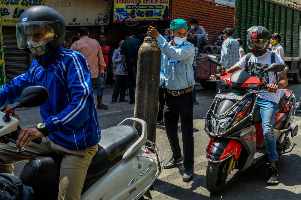 People pick up oxygen cylinders for COVID-19 patients at a shop in Delhi, India, on April 24. With India’s health care system overwhelmed by its unprecedented COVID-19 surge, desperate relatives and friends of the infected have resorted to pleas on social media, and many are reaching tech-savvy engineers, lawyers, NGO workers, politicians, doctors and even tuk-tuk drivers, that have mobilized online to help the sick. (Atul Loke/The New York Times)