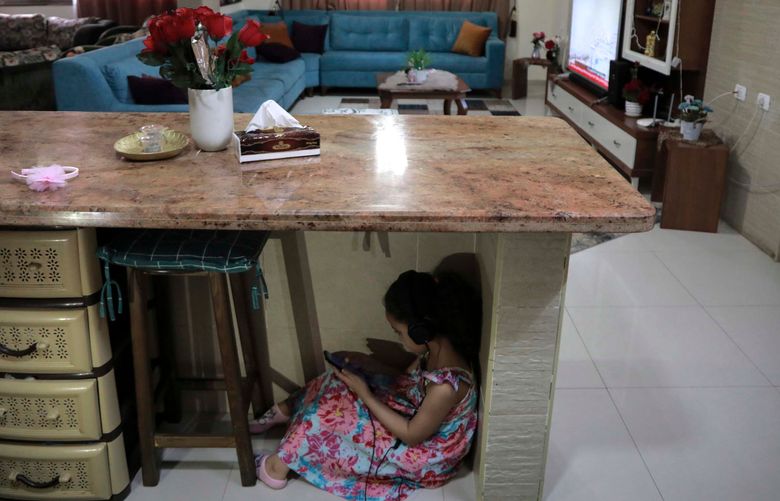Joury Mghames, 7, hides under a counter in the kitchen of her home in Gaza City during Israeli bombing on May 19, 2021. MUST CREDIT: Photo for The Washington Post by Loay Ayyoub
