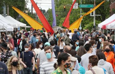 Customers are seen at the Ballard Farmers Market in an entrance stretch of vendors, Sunday, May 30, 2021 in Seattle. According to Doug Farr, executive director of the Seattle Farmers Market Association, the number of customer capacity goes up with the number of vendors, and those have gone up with local harvest produce heading into the end of spring. 320 customers are allowed in, and according to Farr, usually only regular customers will wait in lines to get in (since tourists and cruise traffic is gone). The market looks crowded but Farr points out this is actually way down compared to pre-pandemic Sundays of 18-20,000 customers. 217279