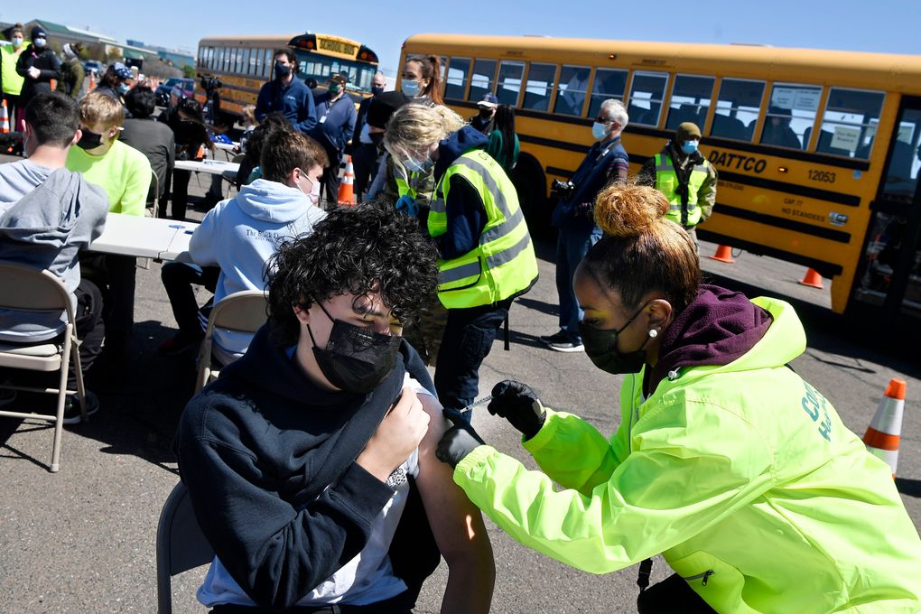 FILE – In this April 26, 2021, file photo, CREC Academy of Aerospace and Engineering sophomore Brian Acevedo, 16, receives a COVID-19 vaccine from nurse Myra Glass, of East Hartford, during a mass vaccination site at Pratt & Whitney Runway in East Hartford, Conn. Teams of experts are projecting COVID-19’s toll on the U.S. will fall sharply by the end of July, according to research released by the government Wednesday, May 5. (AP Photo/Jessica Hill, File)