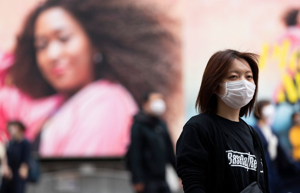 A woman wearing a face mask waits for the traffic lights to change at the famed Shibuya crossing in Tokyo on Thursday, May 20, 2021. (AP Photo/Hiro Komae)
