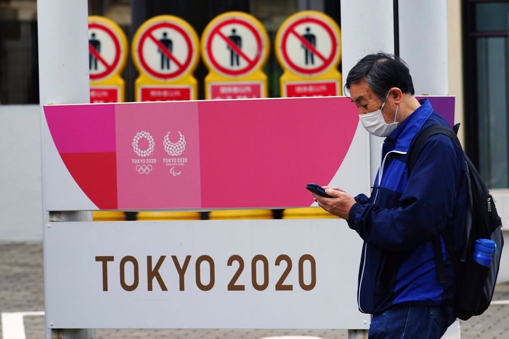 A man wearing a protective mask to help curb the spread of the coronavirus walks past a banner for the Tokyo 2020 Olympic and Paralympic Games in Tokyo Tuesday, May 11, 2021. The Japanese capital confirmed more than 920 new coronavirus cases on Tuesday. (AP Photo/Eugene Hoshiko)
