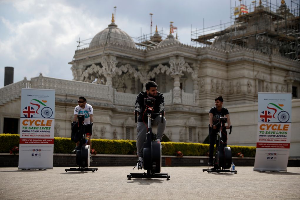 People take part in “Cycle to Save Lives” a 48 hour, non-stop static relay cycle challenge at the BAPS Shri Swaminarayan Mandir, also know as the Neasden Temple, the largest Hindu temple in the UK, in north London, to raise money to help coronavirus relief efforts in India, Saturday, May 1, 2021. (AP Photo/Matt Dunham)