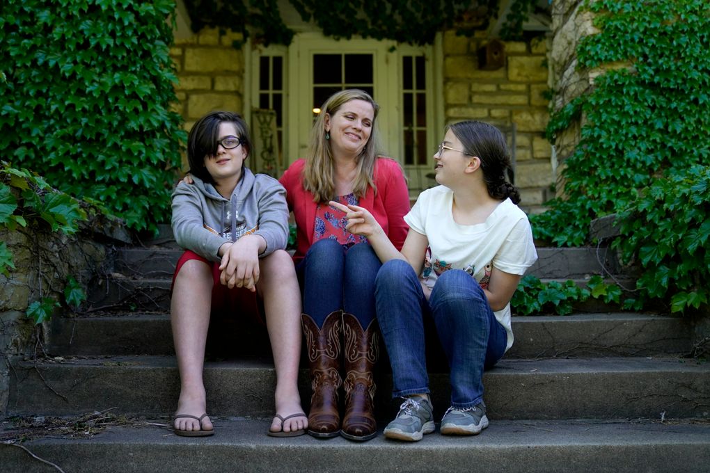 Heather Ousley sits with her older children Elliannah, 15, right, and Samuel, 13, in front of their home in Merriam, Kan, Tuesday, May 4, 2021. Ousley was thrilled when she heard the FDA was expected to authorize Pfizer’s COVID-19 vaccine for youngsters ages 12 to 15 and was hoping to get her kids vaccinated as soon as she can. (AP Photo/Charlie Riedel)