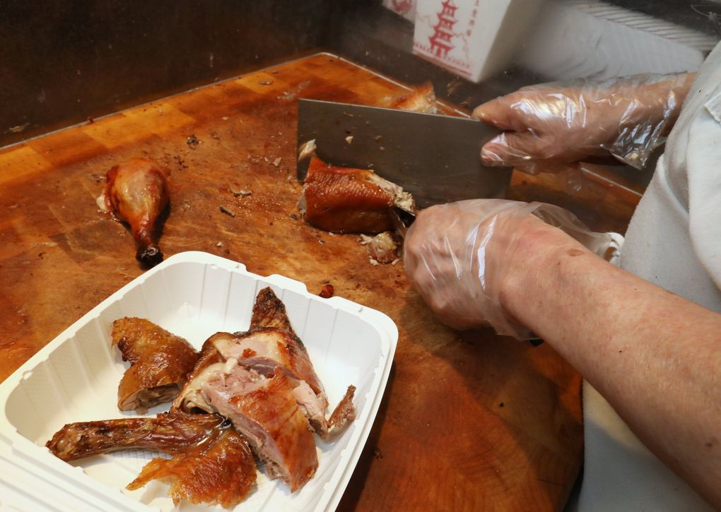 Half of a roasted duck is cut for takeout at Kau Kau Barbecue May 20, 2021, in Seattle’s Chinatown International District. (Ken Lambert / The Seattle Times)