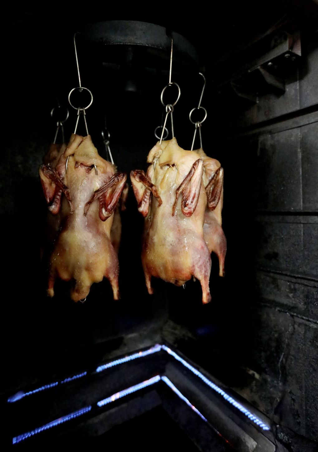 Marinated ducks just put into the oven for roasting are seen in the kitchen at Kau Kau Barbecue May 20, 2021. (Ken Lambert / The Seattle Times)