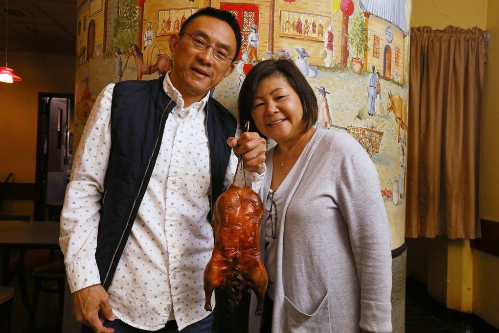 Kau Kau Barbecue owners Richard Chang and his wife Lynn Eng Chang with one of the many roasted ducks they have served here in the Chinatown ID over the decades. (Ken Lambert / The Seattle Times)