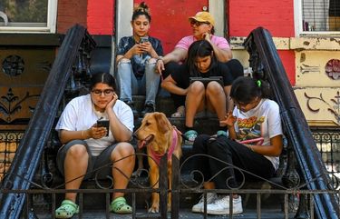 The Flores family online outside their apartment in the Mott Haven section of the Bronx on May 27, 2021. About 13.6 million urban households do not have a broadband connection, according to the Census Bureau. (Desiree Rios / The New York Times)