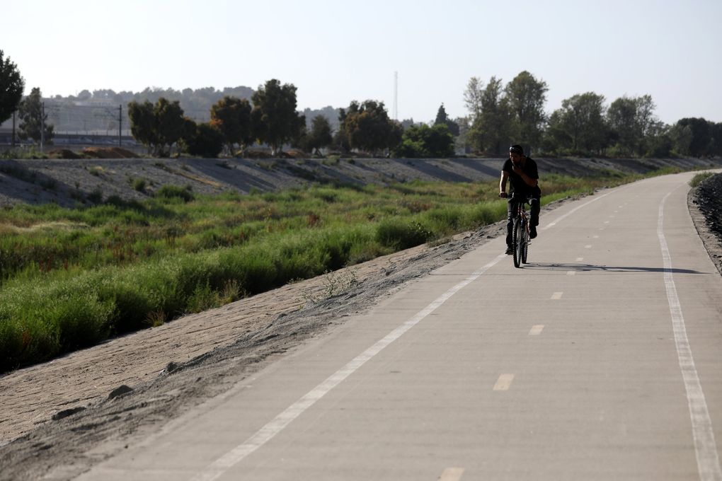 A bicyclist rides along the Compton Creek just north of Del Amp Boulevard where the body of Kenneth Jones, 26, was found on one of the creek’s banks in January. A homeless man, Tracy Walker, 56, is accused of killing three homeless people over the last year in an area of the Compton Creek near Del Amo Boulevard. (Gary Coronado / Los Angeles Times / TNS)