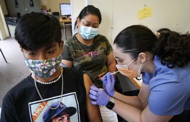 Andreea Marian, right, gives a COVID-19 vaccine to Cristian Hernandez, 16, as his mother Gabina Morales, who had her vaccine moments earlier, looks on at a vaccination clinic at PeaceHealth St. Joseph Medical Center Thursday, June 3, 2021, in Bellingham, Wash. (AP Photo/Elaine Thompson) WAET101 WAET101