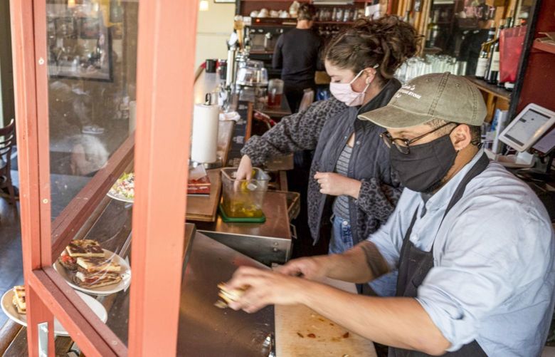 Workers wearing protective masks prepare food inside a restaurant in San Francisco, California, U.S., on Thursday, May 6, 2021. San Francisco advanced into the least restrictive tier of California’s color-coded reopening system Tuesday, allowing most businesses to expand capacity, bars to start serving indoors and large gatherings to resume inside and outside. 775652180