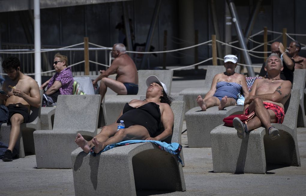 People sunbathe near the beach in Barcelona, Spain, Tuesday, June 8, 2021. Spain is jumpstarting its summer tourism season by welcoming vaccinated visitors from most countries as well as European visitors who can prove they are not infected with coronavirus. (AP Photo/Emilio Morenatti)