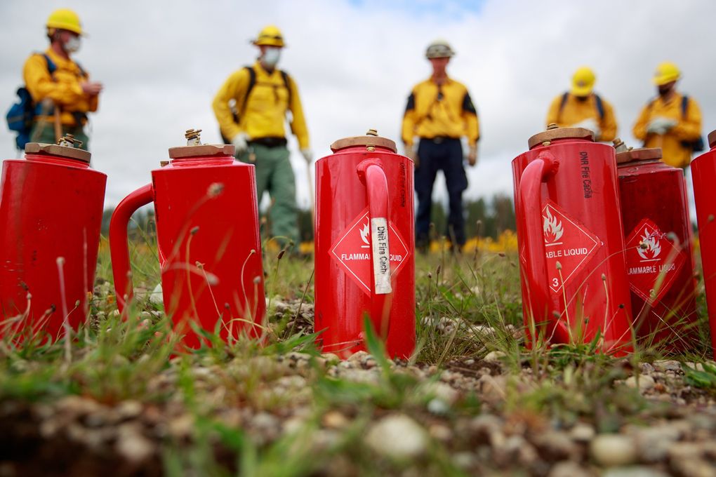 National Guardsmen learn how to use drip torches, red canisters in foreground, during a wildfire training at Joint Base Lewis-McChord. (Erika Schultz / The Seattle Times)