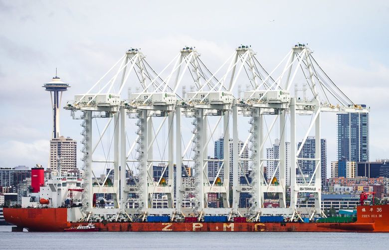 Four new ZPMC Super-Post Panamax shipping cranes pass the Space Needle as they traverse Elliott Bay Sunday January 13, 2021 on the final step of their journey from China. Among the largest on the west coast, the cranes will be installed at Terminal 5 as part of a large modernization project. The viewpoint is from Harbor Avenue Southwest in West Seattle, looking towards the Seattle waterfront. 217381
