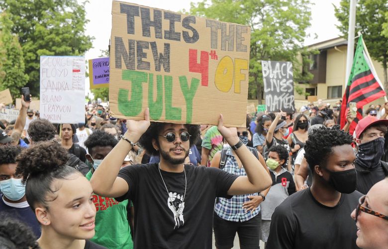 A person taking part in a Juneteenth march in Seattle holds a sign that reads “This the new 4th of July,” Friday, June 19, 2020. Thousands of people marched to honor the Juneteenth holiday and to protest against police violence and racism. (AP Photo/Ted S. Warren) WATW216