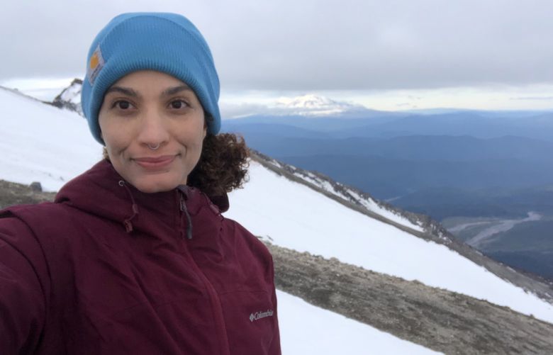 Melissa Hellmann on Mt St Helens with Mount Rainier in the background.