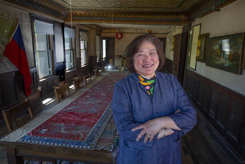 Beth Takekawa, who will retire from Wing Luke Museum after 14 years as executive director and more than 20 years of museum leadership, stands in the old Association Hall on the third floor. The long table  was built in the room from old-growth timber. Meetings and gatherings took place in the room. (Ellen M. Banner / The Seattle Times)