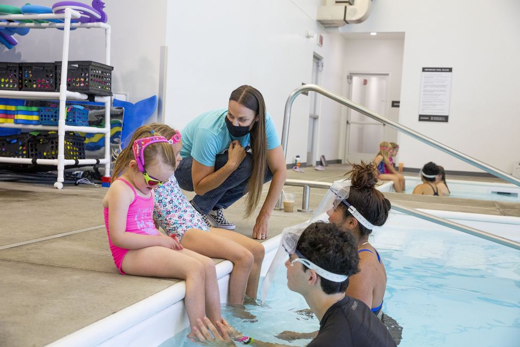 Former Olympic swimmer Amanda Beard, 39, talks with Reagan Randolph,6, and Clara Young, 5, during their swim lesson on Thursday, June 24, 2021 at Beard Swim Co. Beard now runs and teaches swim lessons for kids. (Sylvia Jarrus / The Seattle Times)