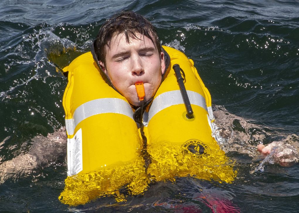 During a training drill with the King County Sheriff’s Office earlier this month, after his self-acting inflatable personal flotation device has inflated, Nathan Loutsis, an explorer for the King County Sheriff’s Office, blows a whistle after he falls into the water off of Carillon Point in Kirkland. (Ellen M. Banner / The Seattle Times)