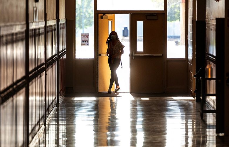 As the sunrise shines through the windows, a student walks into a quiet hallway long before the first bell rings to start class at Clarkston High School on Thursday, Aug. 27, 2020, in Clarkston, Wash.