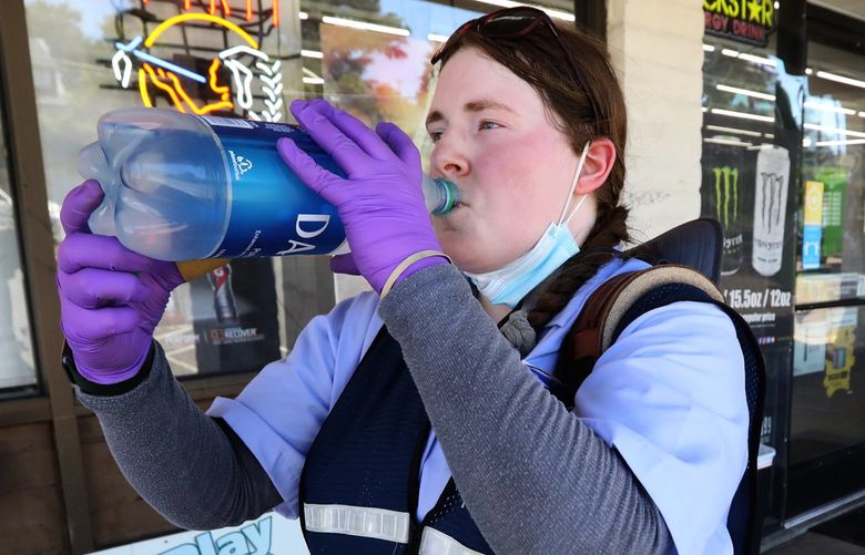 U.S. Postal Service letter carrier Alexis Chumney takes a long drink in front of a Wedgwood convenience store as temperatures pass a hundred degrees, Monday, June 28, 2021 in Seattle. Chumney, 28, is working a longer day than usual after some of her colleagues didn’t make it into work during the record heat. 217515