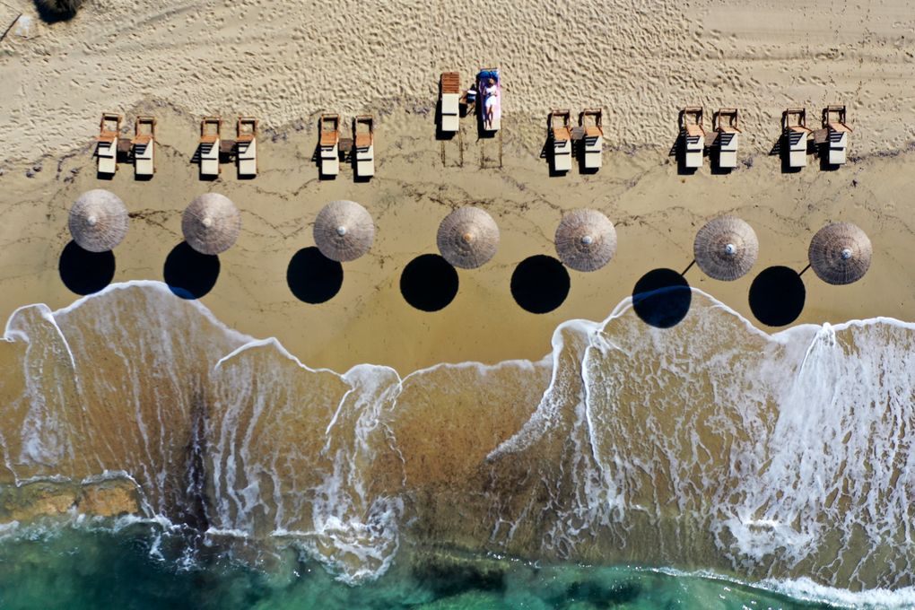 A woman enjoys the sun at Plaka beach on the Aegean island of Naxos, Greece, Friday, May 14, 2021. Greece launched its tourism season Friday amid a competitive scramble across the Mediterranean to lure vacationers emerging from lockdowns. (AP Photo/Thanassis Stavrakis)