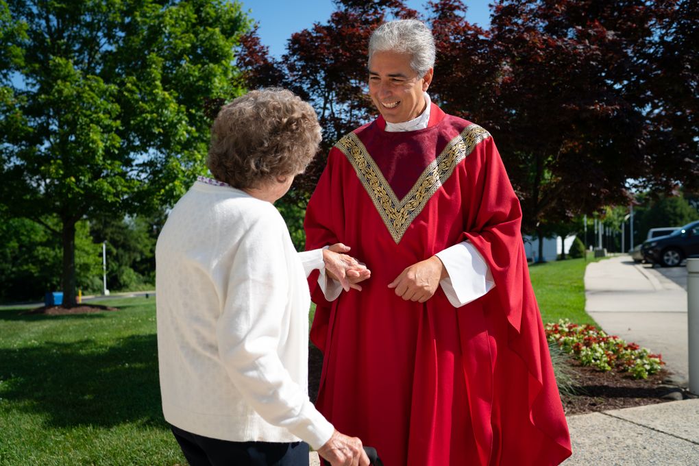 Monsignor Edward Filardi of St. Paul Catholic Church in Damascus, Md., greets his community after a Saturday service on June 5. He is holding the hand of Virginia Rhodes, an original members of the parish who will be turning 100 on July 17. (Washington Post photo by Sarah L. Voisin).