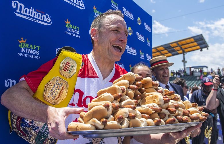 Winners Joey Chestnut and Michelle Lesco, obscured behind hot dogs, pose at the Nathan’s Famous Fourth of July International Hot Dog-Eating Contest in Coney Island’s Maimonides Park on Sunday, July 4, 2021, in the Brooklyn borough of New York. (AP Photo/Brittainy Newman) NYBN115 NYBN115