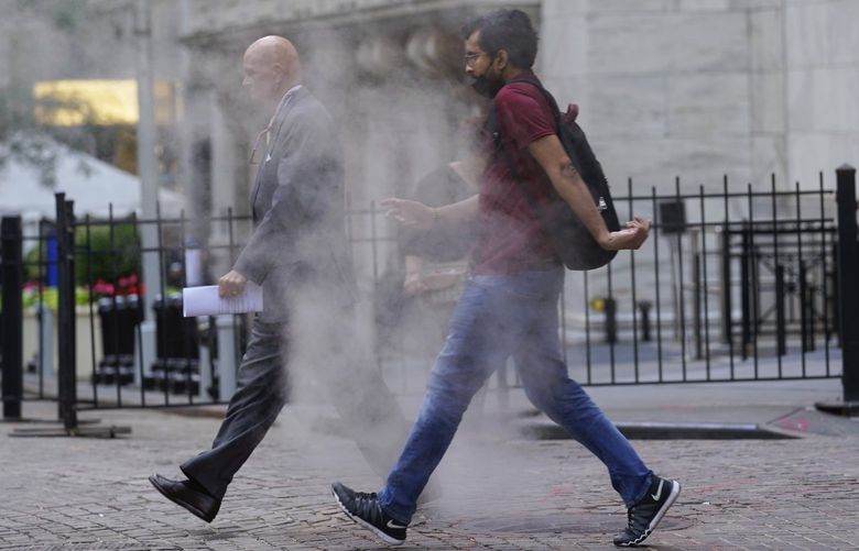 FILE – In this June 16, 2021 file photo, people walk through steam from a street grating during the morning commute in New York.   Companies around the U.S. are scrambling to figure out how to bring employees back to the office after more than a year of them working remotely. Most are proceeding cautiously, trying to navigate declining COVID-19 infections against a potential backlash by workers who are not ready to return. (AP Photo/Richard Drew) NYBZ305 NYBZ305