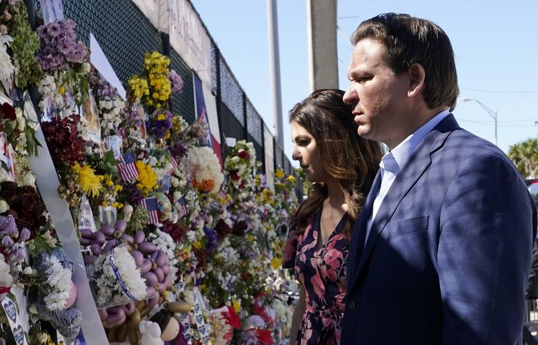 FILE – In this July 3, 2021, file photo Florida Gov. Ron DeSantis, right, and his wife Casey tour a makeshift memorial near the Champlain Towers South condo building, where scores of victims remain missing more than a week after it partially collapsed in Surfside, Fla. As he prepares for a reelection bid next year that could propel him into a presidential campaign, the tragedy in Surfside is exposing voters to a different side of DeSantis. (AP Photo/Lynne Sladky, File) WX203 WX203