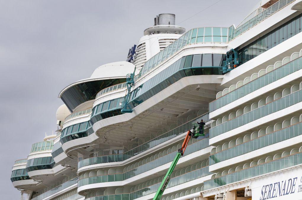 A painter touches up a spot on Royal Caribbean’s ship, Serenade of the Seas, as it bobs in Elliott Bay, tied up at Pier 91 in Seattle July 7, 2021. After a test voyage to Alaska with crew members only aboard, a fully booked cruise with hundreds of passengers will depart from the same Seattle pier on July 19, 2021. (Ellen M. Banner / The Seattle Times)