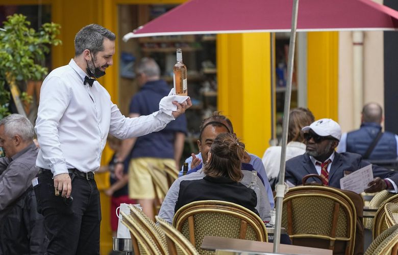 A waiter serves vine at a restaurant terrace in Versailles, west of Paris, Thursday, July 15, 2021. French restaurant owners and workers are as worried as anyone about the virus – but they’re also worried that new mandatory COVID passes will turn them into virus police instead of purveyors of culinary pleasures.Starting next month, all diners in France must show a pass proving they’re fully vaccinated, or recently tested negative or recovered from the virus. (AP Photo/Michel Euler) MEU101 MEU101
